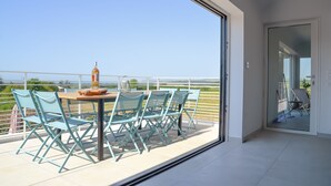 Un balcon avec une table et des chaises, une bouteille et une vue sur le paysage.