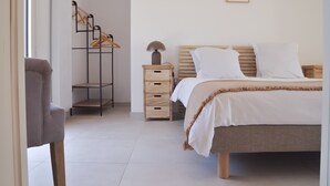 Une chambre bien rangée, avec un lit, une table de chevet, une lampe et un portant à vêtements.