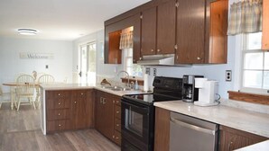Une cuisine moderne avec des meubles en bois, une cuisinière noire et un lave-vaisselle.