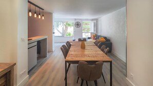A modern kitchen with a wooden dining table, chairs, and pendant lights. - 3 bedroom beach front apartment in Agde (Agde)