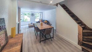 A dining area with a wooden table and chairs, a clock on the wall, and a staircase to the right. - 3 bedroom beach front apartment in Agde (Agde)