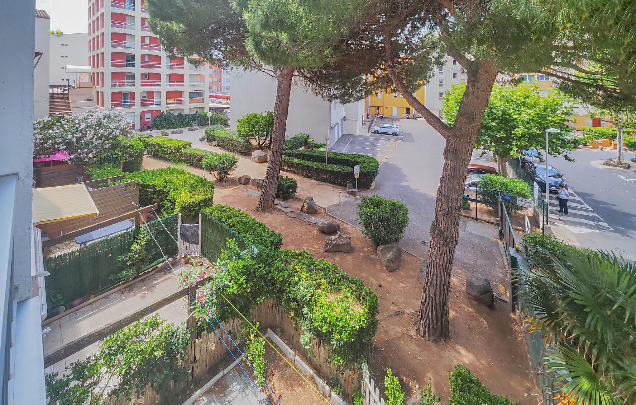 Un quartier résidentiel doté d’un chemin pavé, d’arbres et d’un immeuble avec des balcons.