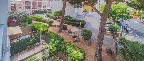 Un quartier résidentiel doté d’un chemin pavé, d’arbres et d’un immeuble avec des balcons.