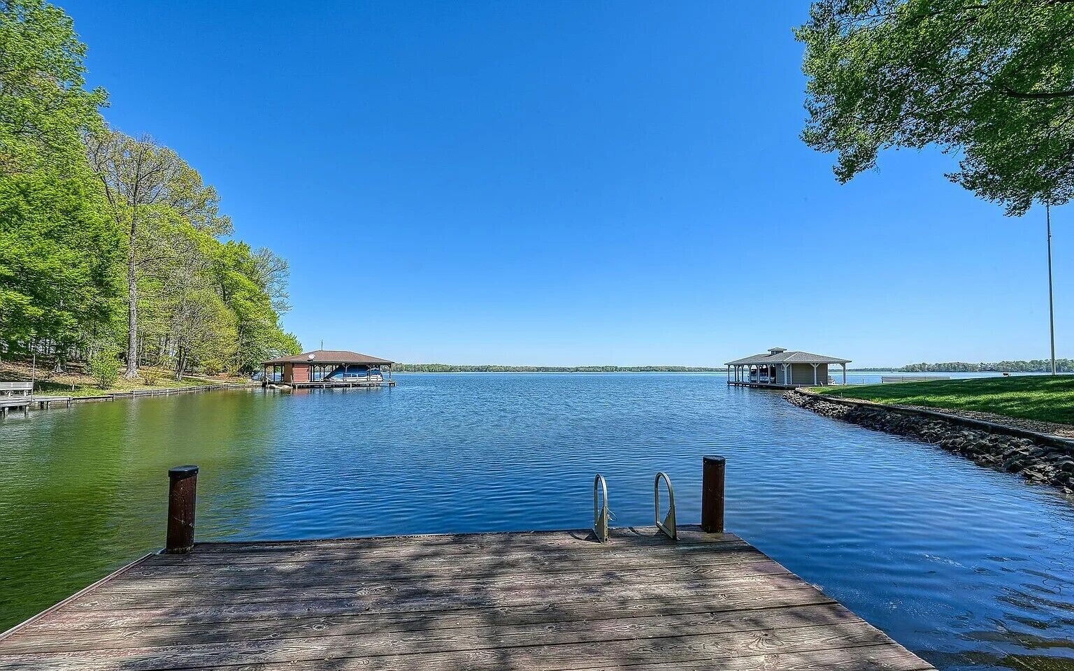 A wooden dock extending into a calm lake with clear skies.