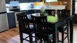 A modern kitchen with dark cabinets, stainless steel appliances, and a dining area with a table and chairs.