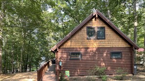 A wooden cabin with a porch, surrounded by trees.