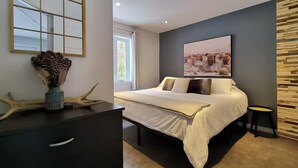 A modern bedroom with a bed, bedside table, and a large window. - 5 minutes from the Bras du Nord Valley / Chalet with riverfront spa (Saint-Raymond)