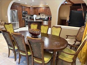A dining area with a wooden table and chairs, a decorative bowl, and a kitchen in the background.