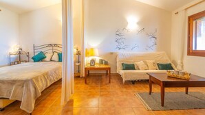 Ein gemütliches Schlafzimmer mit einem Bett, einer Couch, einem kleinen Tisch und einer Wandleuchte.