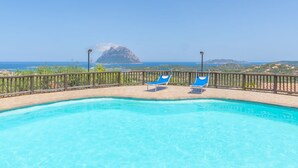 Ein klarer, blauer Swimmingpool mit zwei blauen Liegestühlen und einem Holzzaun.