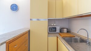 Une cuisine de taille réduite avec des meubles de couleur jaune, un four à micro-ondes, un grille-pain et un évier.