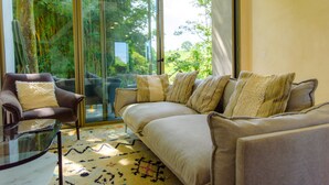 A modern living room with a sofa, armchair, and glass coffee table. - Casa del Rio, a little oasis 15 minutes from the airport (Alajuela)