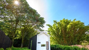 A small, modern house with a white exterior and dark roof, surrounded by lush greenery and trees. - Casa del Rio, a little oasis 15 minutes from the airport (Alajuela)