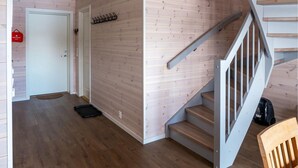 Un intérieur en bois avec un escalier, une trousse de premiers secours et un porte-manteau.