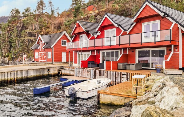A row of red wooden houses with a dock and boats.