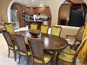 A dining area with a wooden table and chairs, a decorative bowl, and a kitchen in the background. - Welcome To my beautiful home (Las Vegas)