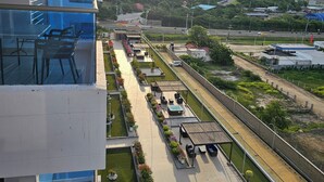 Terraço de hotel com área de estar externa, piscina e vista do horizonte circundante, incluindo uma estrada e vegetação.