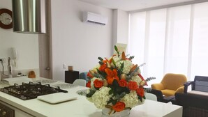 Uma cozinha moderna com uma ilha central, fogão a gás e bancada branca.