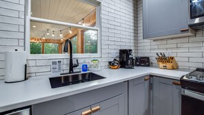 A modern kitchen with a sink, countertop, and wooden cabinets.