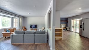 A spacious living area with a grey sofa, wooden flooring, and a television.