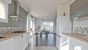 A modern kitchen with a central island, white cabinetry, and a view to the outside.