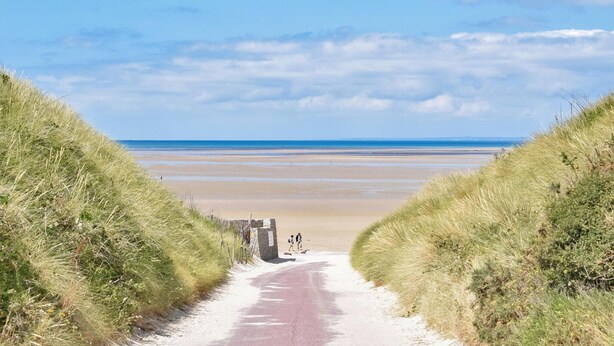 A pathway leading to a beach with a clear sky.