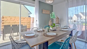 A dining area with a wooden table set for four, surrounded by wicker chairs.