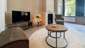 Ein Wohnzimmer mit Fernseher, Kamin, rundem Couchtisch und einer Bank.