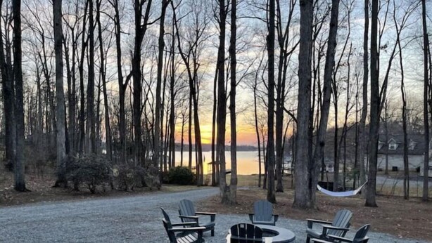 A campsite with four Adirondack chairs, a fire pit, and a hammock. - License To Chill - Lakefront/Screened in Porch (Bumpass)