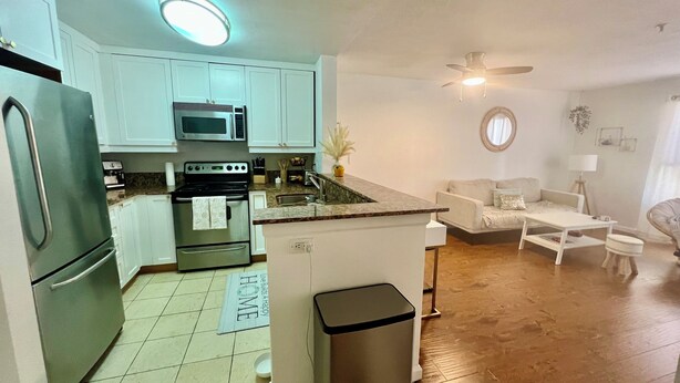 A compact kitchen with a refrigerator, microwave, stove, and sink. There's a small dining area with a white table and chairs. - Prime location, 5 minutes to the Beach, UCSD, Hospitals, UTC Mall  (San Diego)