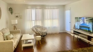A living room with a sofa, armchair, TV, and a ceiling fan. - Prime location, 5 minutes to the Beach, UCSD, Hospitals, UTC Mall  (San Diego)