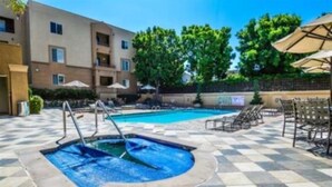 A pool area with a checkered floor, lounge chairs, and umbrellas. - Prime location, 5 minutes to the Beach, UCSD, Hospitals, UTC Mall  (San Diego)