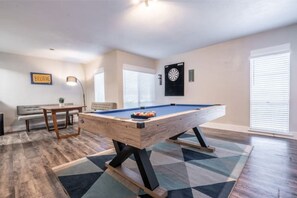 Relax in a comfortable space with a pool table, sofa, and dartboard.