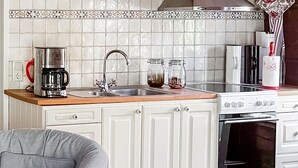 Een keuken met witte kastjes, een roestvrijstalen koffiezetapparaat, een spoelbak en een witte kookplaat.