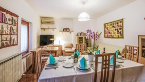 A dining area with a table set for four, a television, a bookshelf, and a decorative wall hanging. - Stunning home in Cividale del Friuli (Cividale del Friuli)