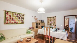 A living room with a sofa, a coffee table, a dining table set for two, and a kitchen area visible through an open door. - Stunning home in Cividale del Friuli (Cividale del Friuli)