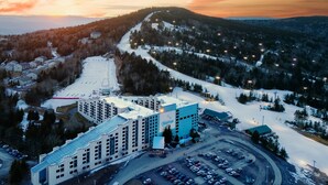 A ski resort with a large building, parking area, and snow-covered slopes. - Ski In/out, Sleeps 8, Pool, Hot Tub, Snow Tubing! (Snowshoe)