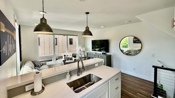 Una cocina moderna con una isla grande, pileta de acero inoxidable e iluminación colgante.