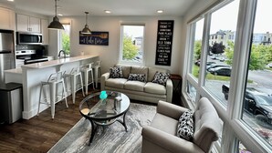 Una cocina moderna con una isla central, taburetes de bar y una mesa de centro de vidrio.