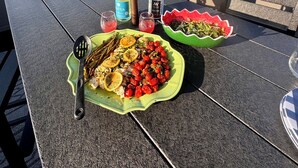 Una mesa en una terraza con comida, una botella de agua y una botella de vino.