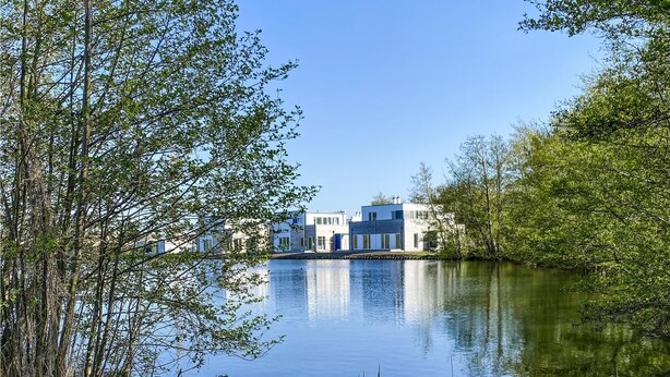 A lakeside property with modern architecture, a calm water body, and lush greenery. - Beautiful home in Tossens with sauna (Tossens)