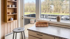 A kitchen with wooden shelves, a granite countertop, a window with a view of trees, and a stool. - Awesome home in Sydals with kitchen (Sydals)