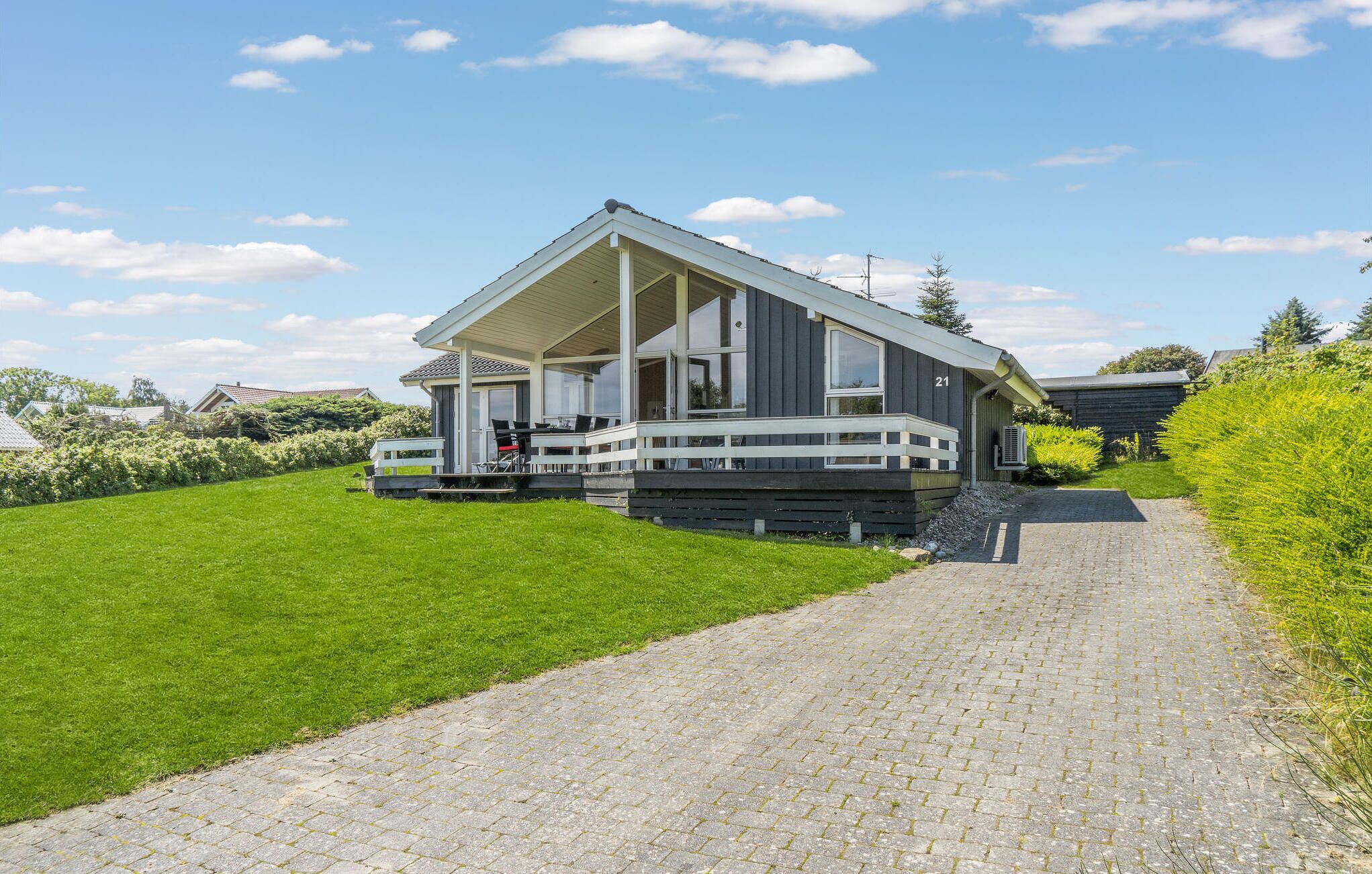Une maison moderne à deux étages, dotée d’un porche couvert et d’une allée pavée.