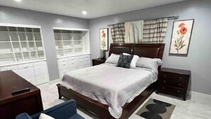 A bedroom with a bed, a desk, a chair, and a wardrobe.