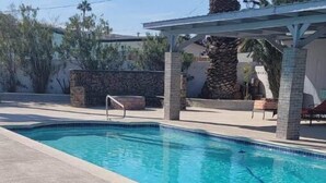 A swimming pool with a hot tub, surrounded by stone pillars and a pergola.