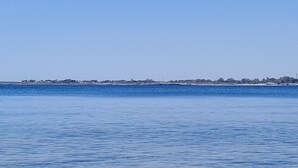 A coastal view with calm waters and a distant shoreline with buildings. - Cozy Little House in town La Ficurinia 🌵 (Siracusa)