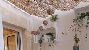 A small, enclosed outdoor space with a sliding glass door, a metal table, and several potted plants. - Cozy Little House in town La Ficurinia 🌵 (Siracusa)