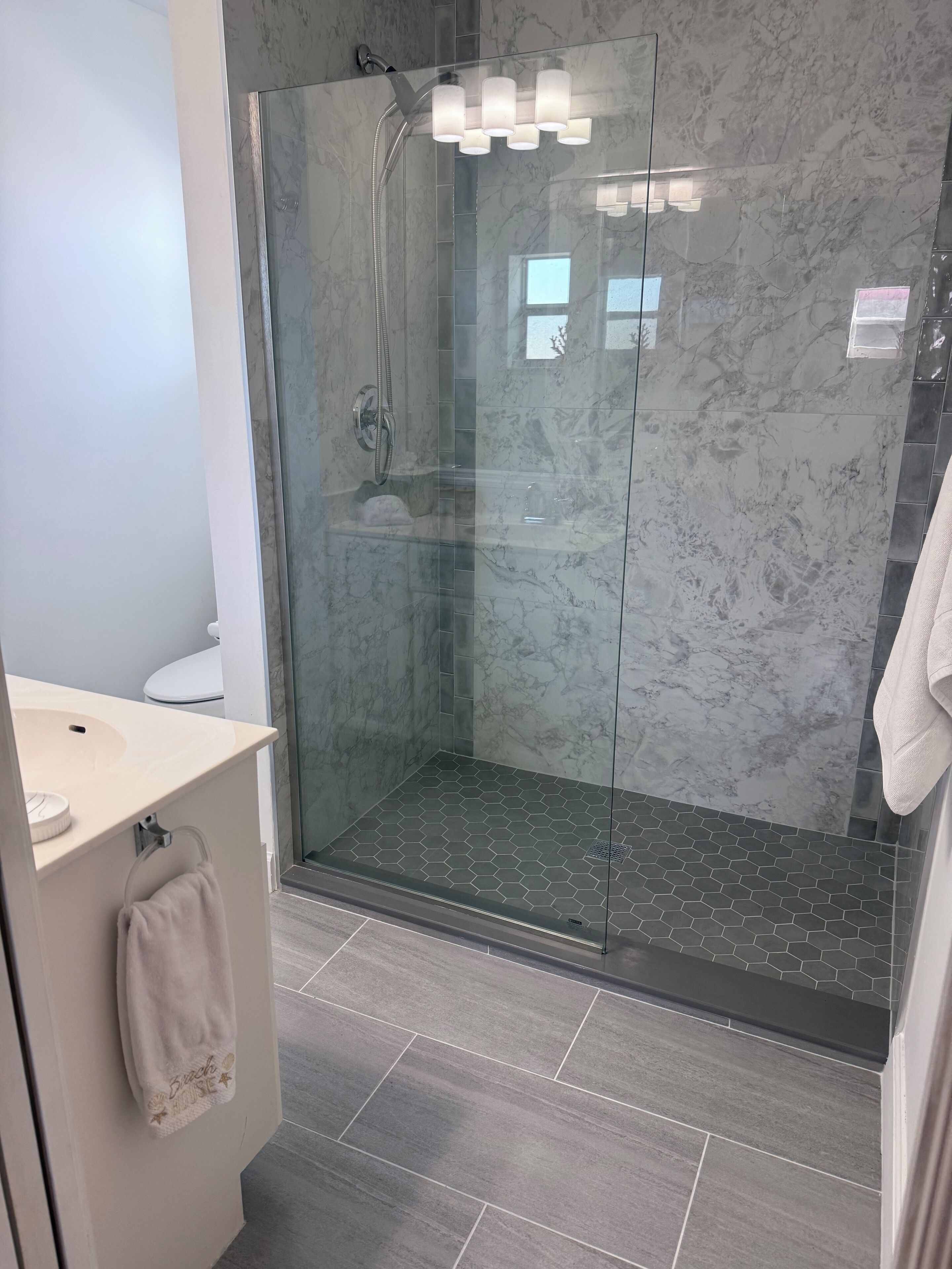 A modern bathroom with a glass-enclosed shower, a beige sink, and a towel rack.