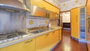 A kitchen with yellow cabinets, stainless steel appliances, and a tiled backsplash. - Cozy apartment in Recco with WiFi (Recco)