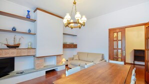 A spacious living room with a wooden dining table, a fireplace, and a chandelier. - Cozy apartment in Recco with WiFi (Recco)